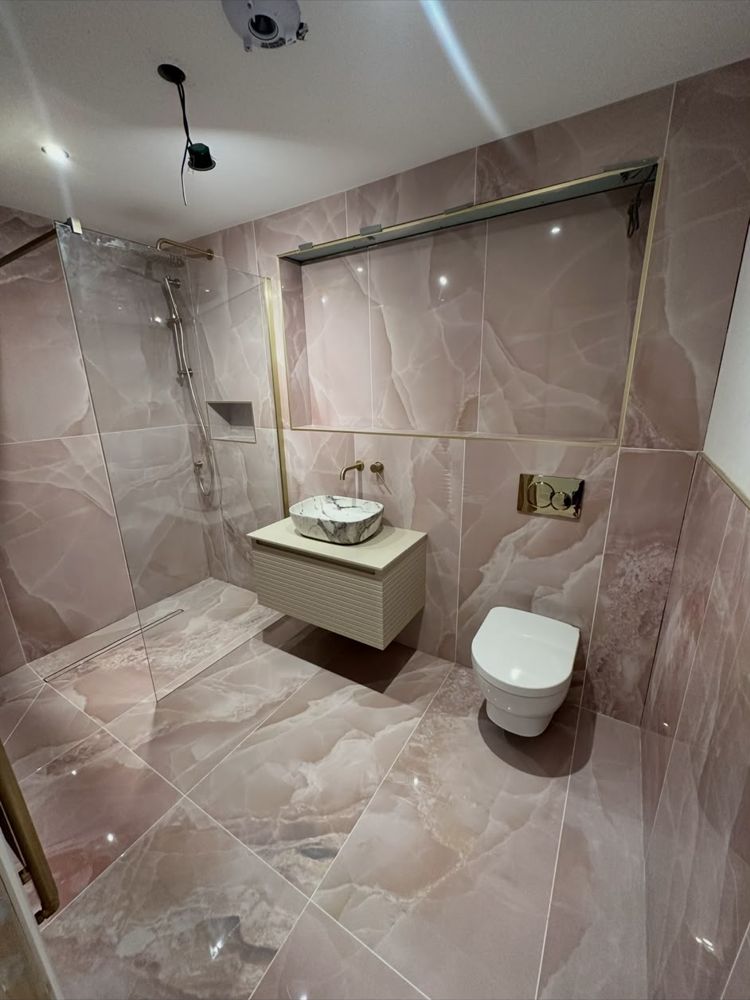 Wet room with pink marble-effect tiles, walk-in shower with linear drain, countertop basin and wall-hung toilet