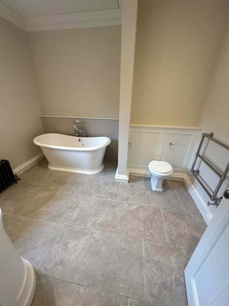 Freestanding roll-top bath with traditional taps and towel rail