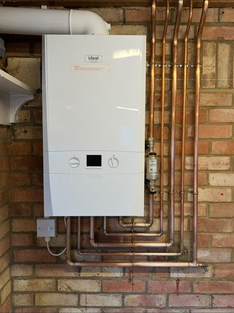 New Ideal combi boiler fitted on a brick wall with neat copper pipework and a magnetic system filter