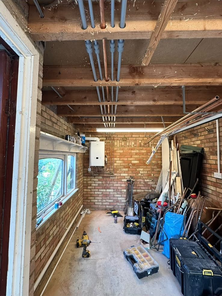Garage during a boiler install, with new pipework run along the ceiling joists to the boiler