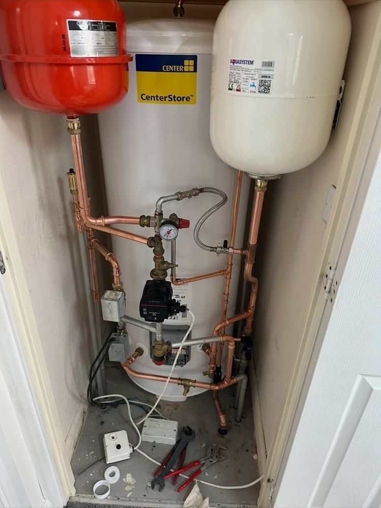 Unvented hot water cylinder in an airing cupboard with expansion vessels and copper pipework
