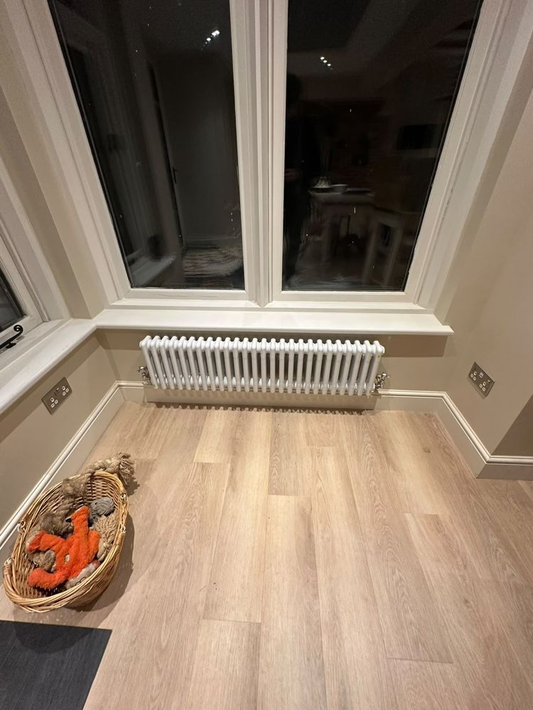 White column radiator fitted under a bay window